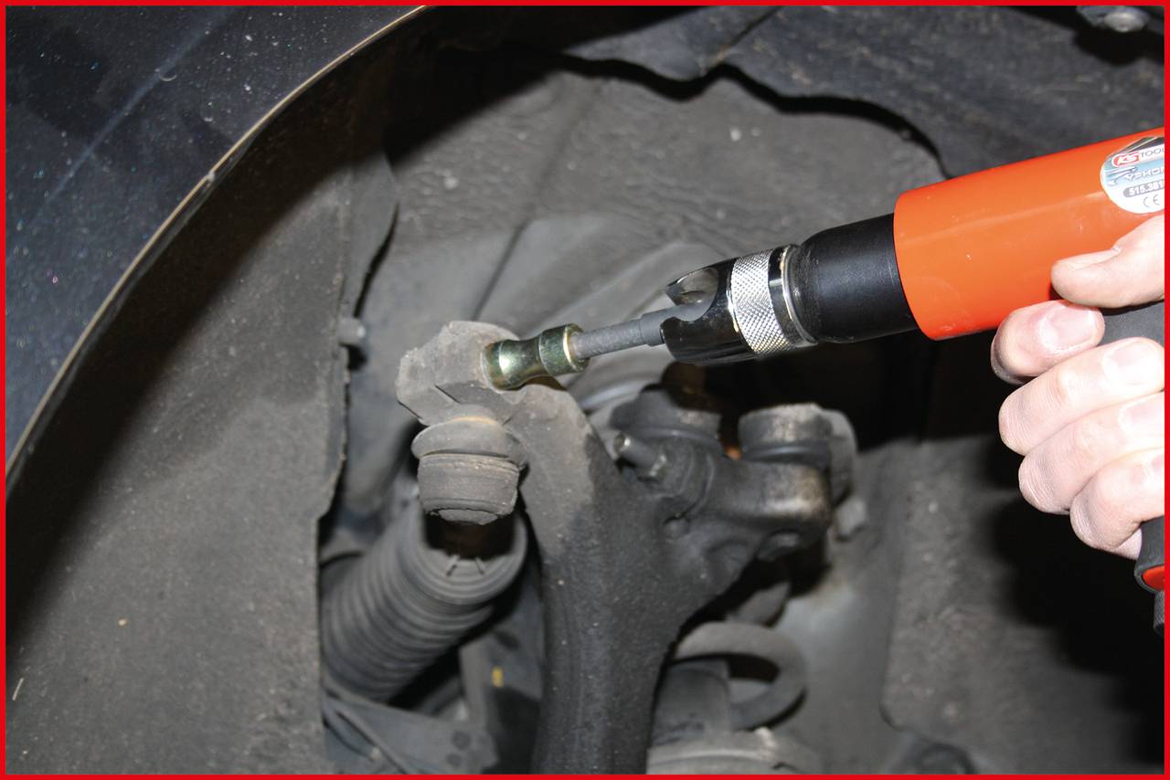 Nahaufnahme eines Werkzeugs zum Entfernen einer Radschraube eines Fahrzeugs. Ein rotes Elektrogerät wird von einer Hand gehalten.