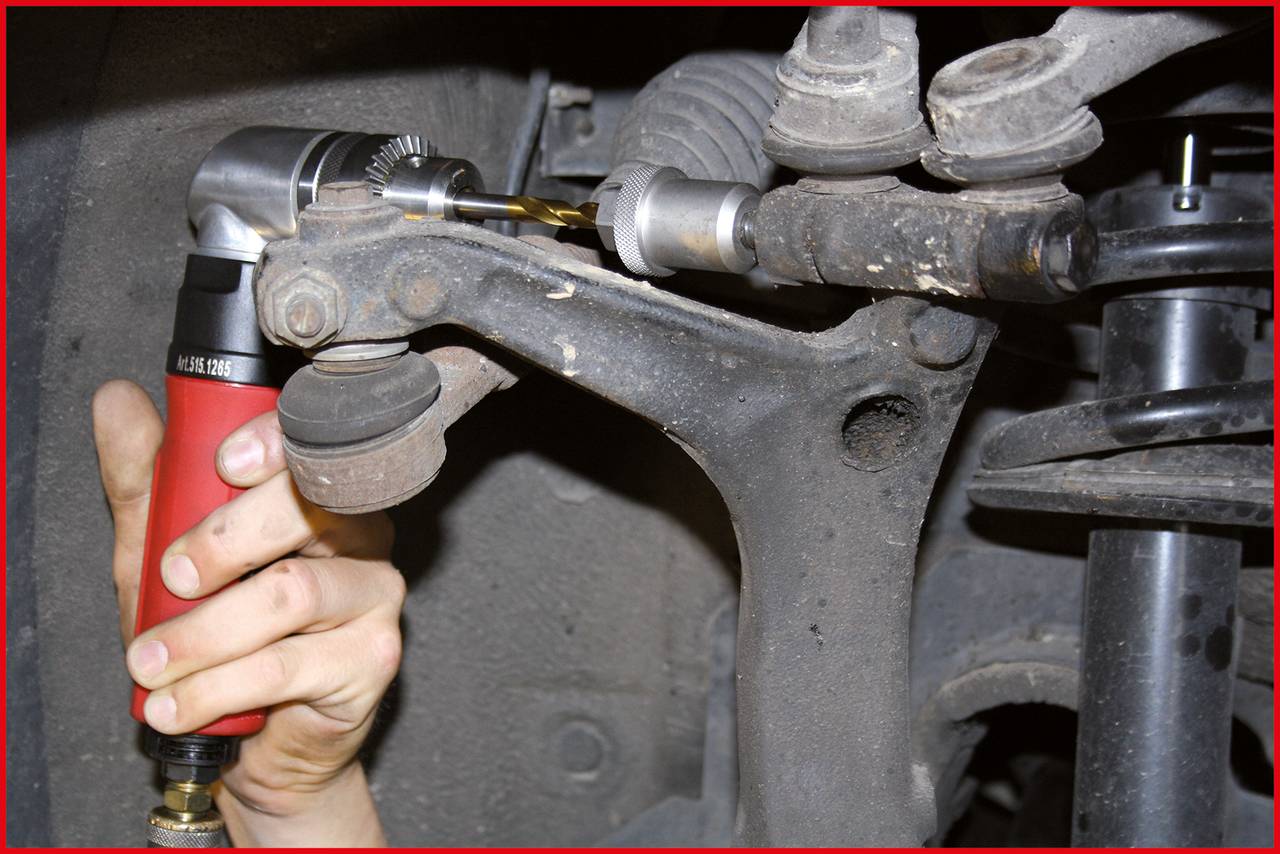 Eine Person verwendet eine Maschine zum Entfernen eines abgenutzten Lenkgestänges von einem Fahrzeug. Klare Sicht auf Mechanik.