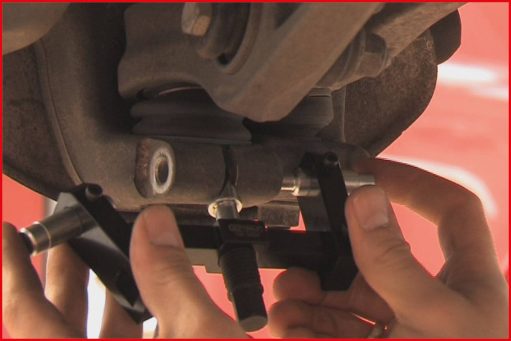 Mechaniker benutzt spezielles Werkzeug, um Fahrzeugbremsen zu reparieren. Nahaufnahme zeigt Details der Reparaturarbeit.