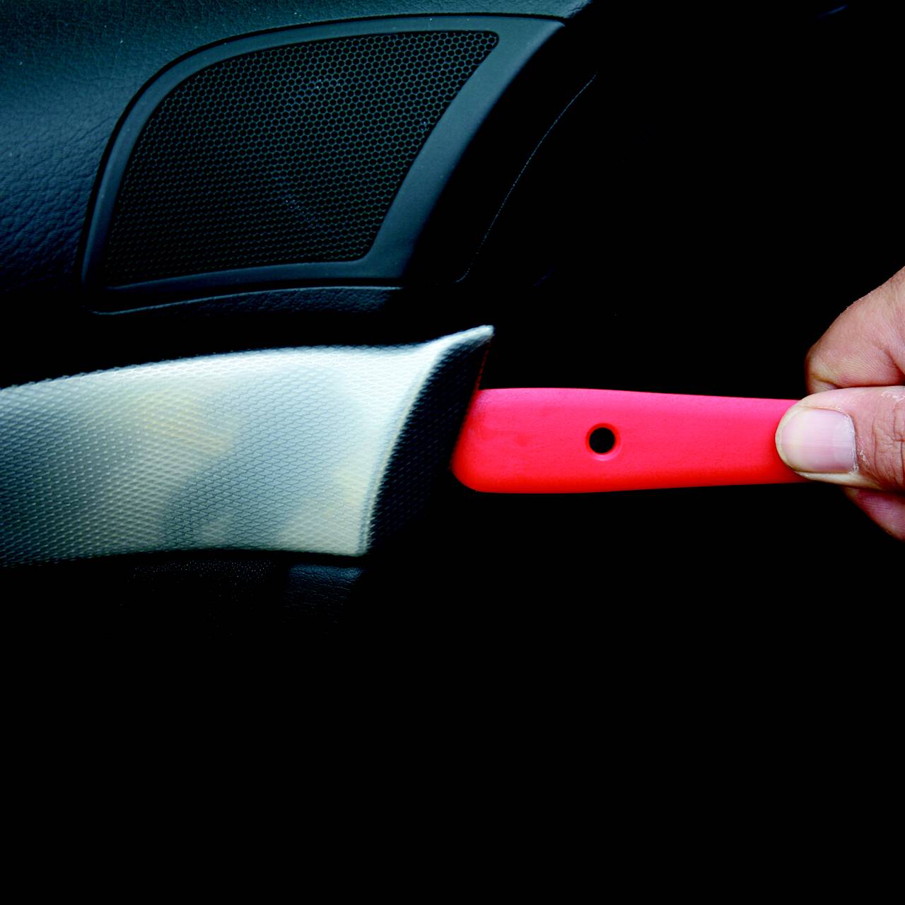 Eine Hand hält ein Messer mit einer roten Klinge vor einem dunklen Hintergrund.