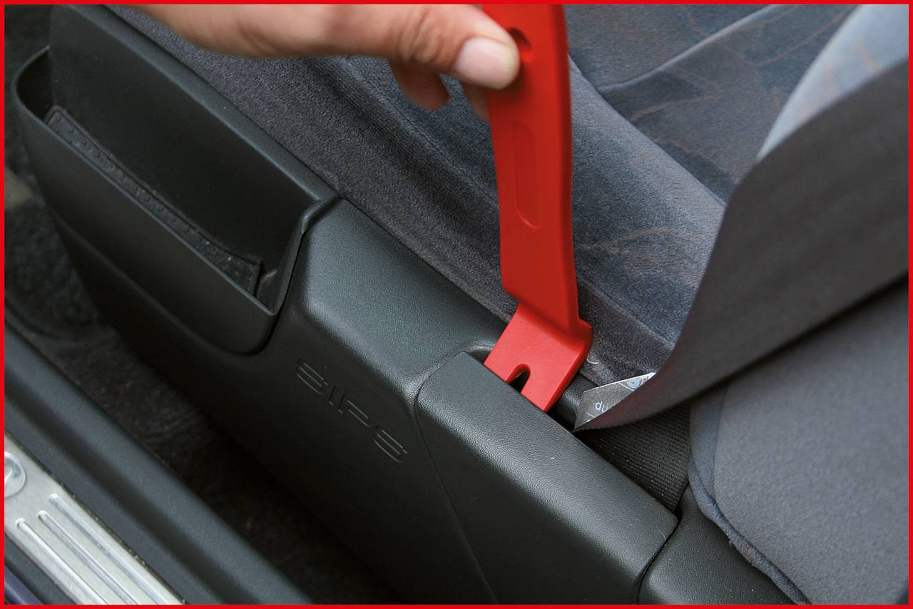 Eine Hand zieht an einer roten Schlaufe, die unter einem Autositz befestigt ist, um sicher auf den Bereich darunter zuzugreifen.