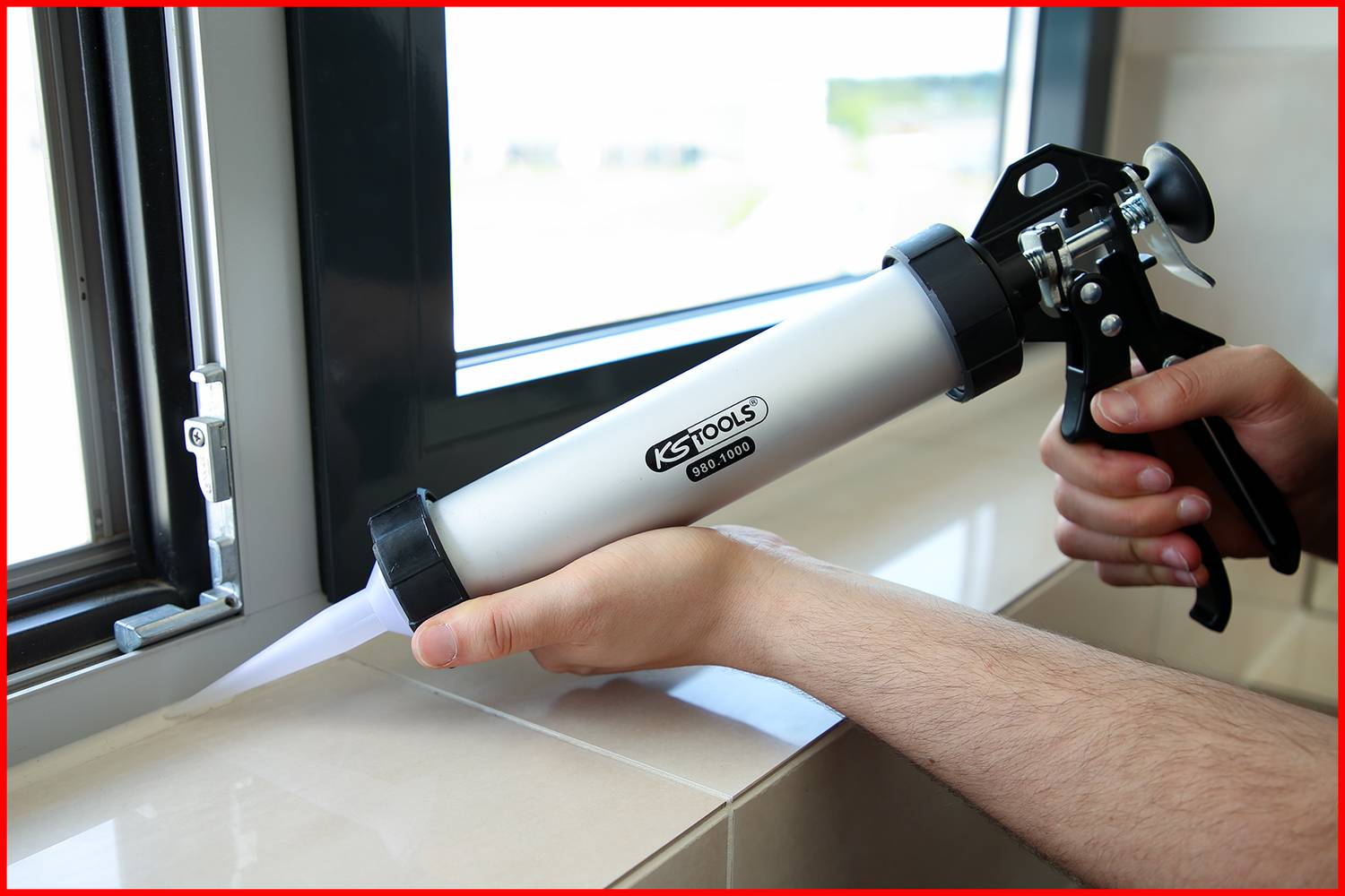 Eine Person dichtet mit einer Kartuschenpistole die Kante eines Fensterrahmens ab.