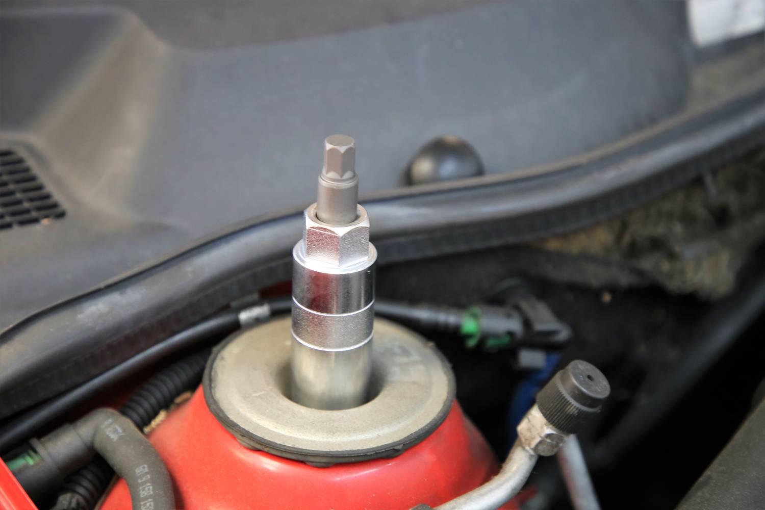 Nahaufnahme eines Stoßdämpfers im Motorraum eines Fahrzeugs, zeigt das obere Ende und Montagekomponenten.