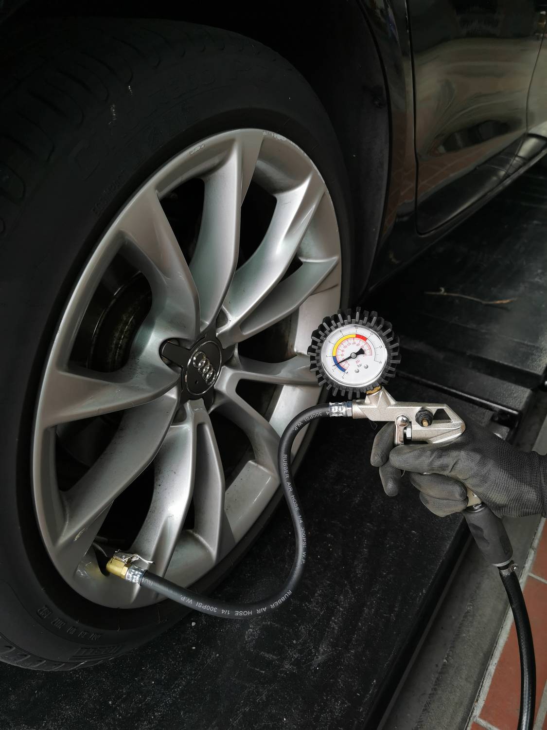 Auto wird auf Luftdruck überprüft; Manometer zeigt Druck an.