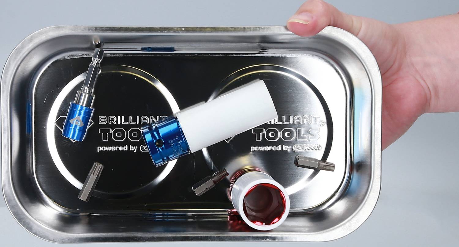 Eine Hand hält ein magnetisches Metalltablett mit verschiedenen Werkzeugaufsätzen, darunter blau und rot markierte Bits.