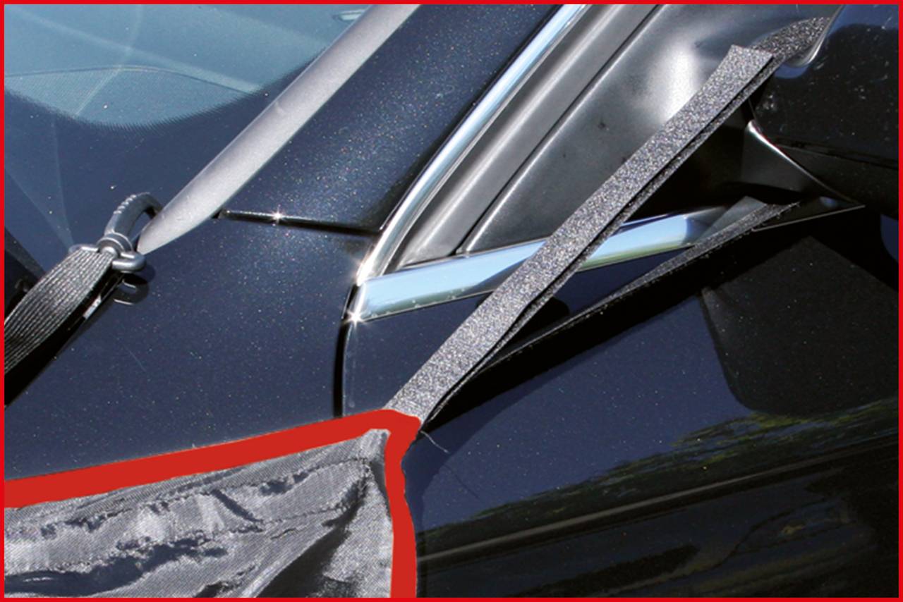 Nahaufnahme eines schwarzen Autoteils, möglicherweise eines Autofensters, mit einem grauen Band darüber. Das Band scheint befestigt zu sein.