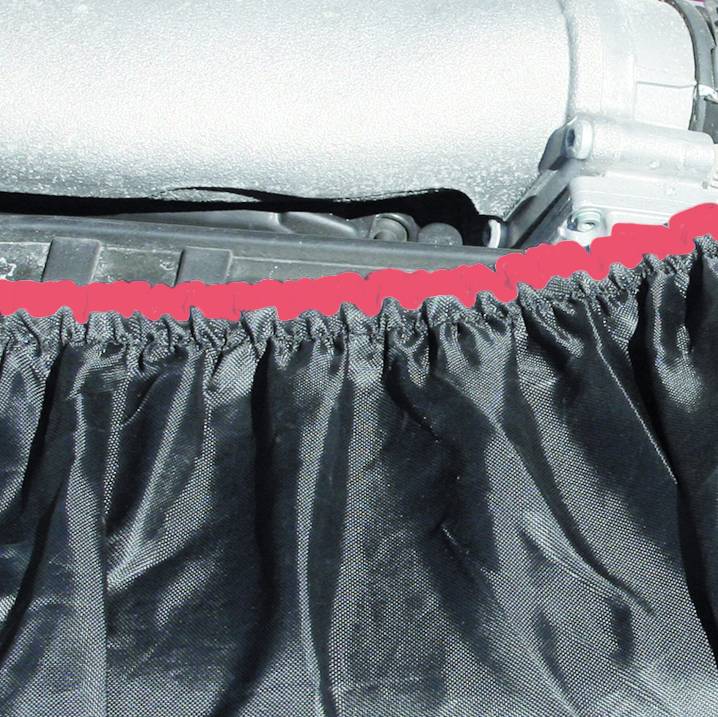 Eine schwarze Abdeckung oder Vorhang verdeckt teilweise einen motorähnlichen metallischen Gegenstand im Hintergrund.