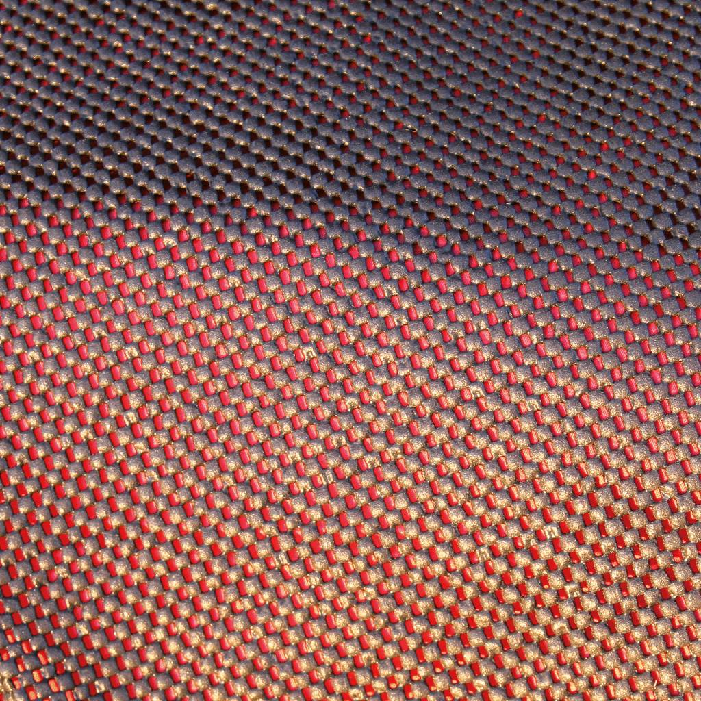 Nahaufnahme eines strukturierten Oberflächenmusters mit roten und goldenen Akzenten, das ein reflektierendes und schimmerndes Aussehen erzeugt.