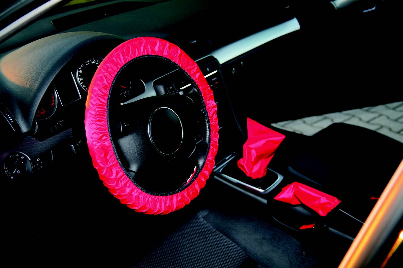 Das Bild zeigt das Innere eines Autos mit einem roten Lenkradschutz. Auch der Schalthebel ist mit einer roten Schutzfolie bedeckt.