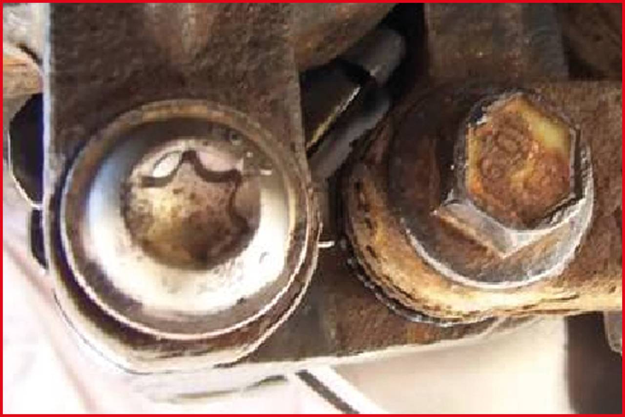 Zwei Schrauben, eine davon leicht rostig, montiert in einer Metallhalterung. Sie halten mechanische Teile zusammen.