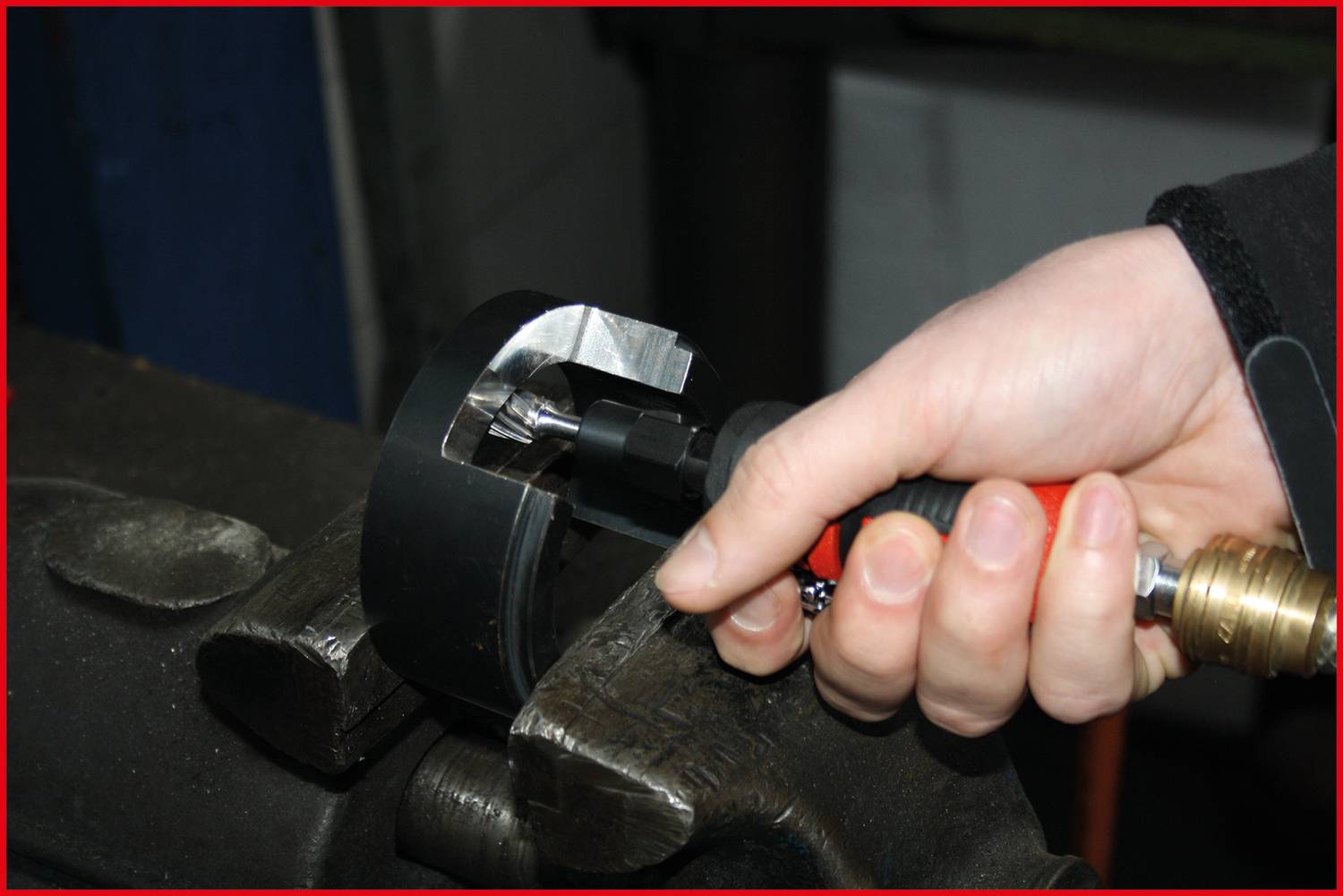 Eine Hand hält ein Drehmomentwerkzeug, das an einem Metallstück in einem Schraubstock angelegt ist, um es zu bearbeiten oder festzuziehen.