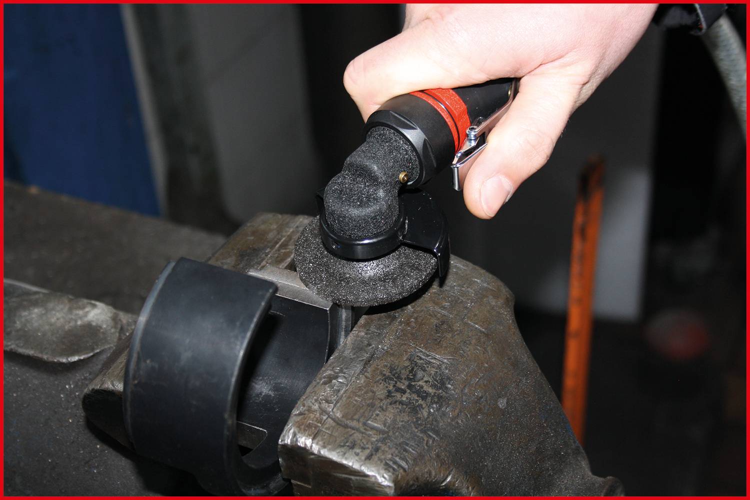 Eine Person schleift mit einem elektrischen Werkzeug eine Metallfläche, um die Oberfläche zu glätten oder Material zu entfernen.