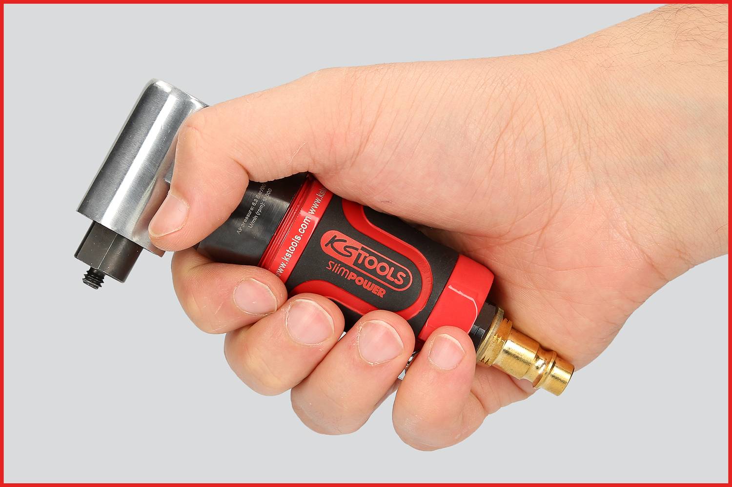 Eine Hand hält ein rotes, modifiziertes Werkzeug mit schwarzem Design und goldener Spitze, vermutlich ein Druckluftgerät.