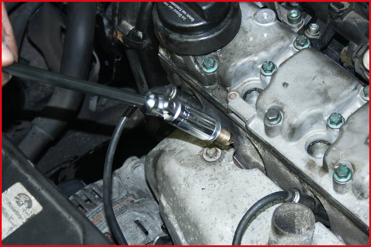 Eine Person prüft den Motor eines Autos mit einer Zündkerzenleuchte. Die Umgebung zeigt verschiedene Motorteile und Kabel.