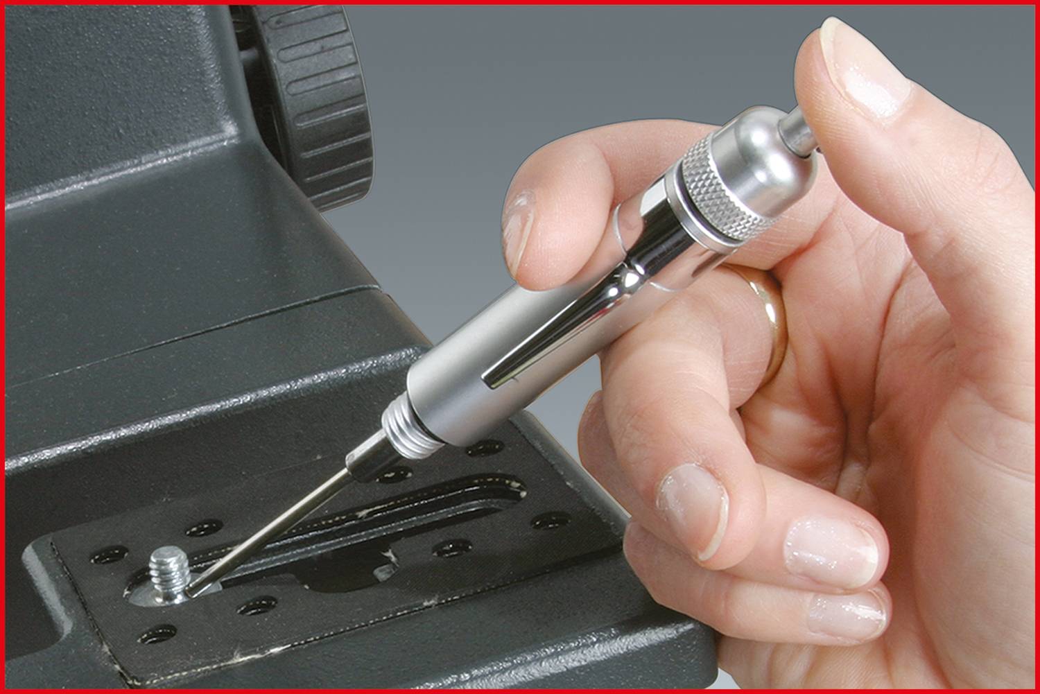 Eine Person verwendet einen Schraubendreher, um eine Schraube in mechanischem Gerät zu befestigen. Nahaufnahme der Hand und des Werkzeugs.