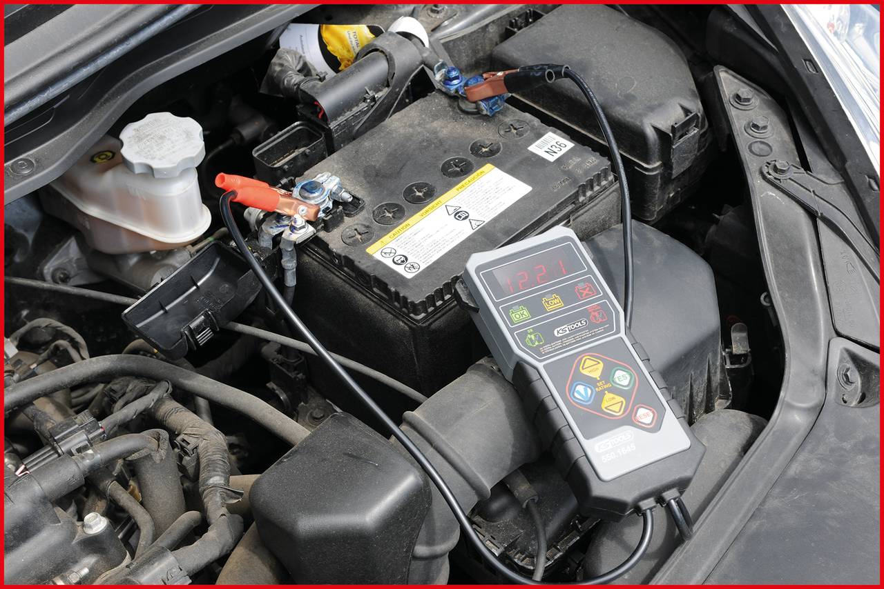 Ein Autobatterie-Ladetest wird mit einem tragbaren Ladegerät durchgeführt, das an die Batterie angeschlossen ist. Batteriestatus wird geprüft.