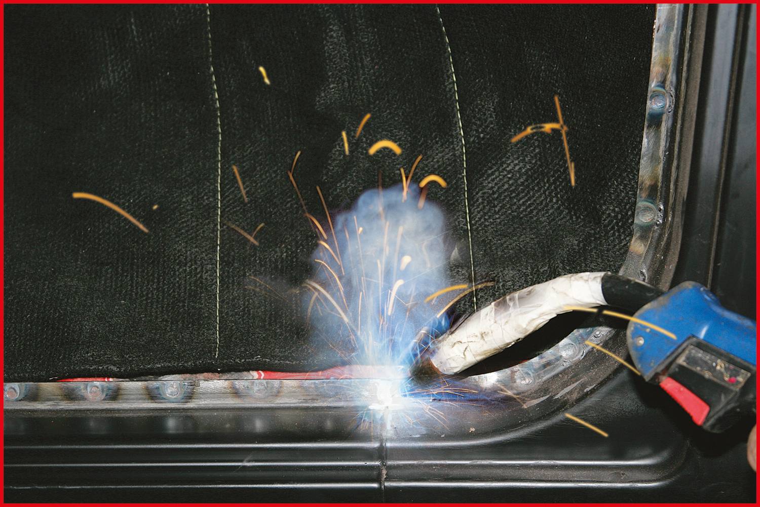 Ein Schweißgerät erzeugt Funken und Rauch, während es an einem Metallstück arbeitet. Der Hintergrund ist unscharf.