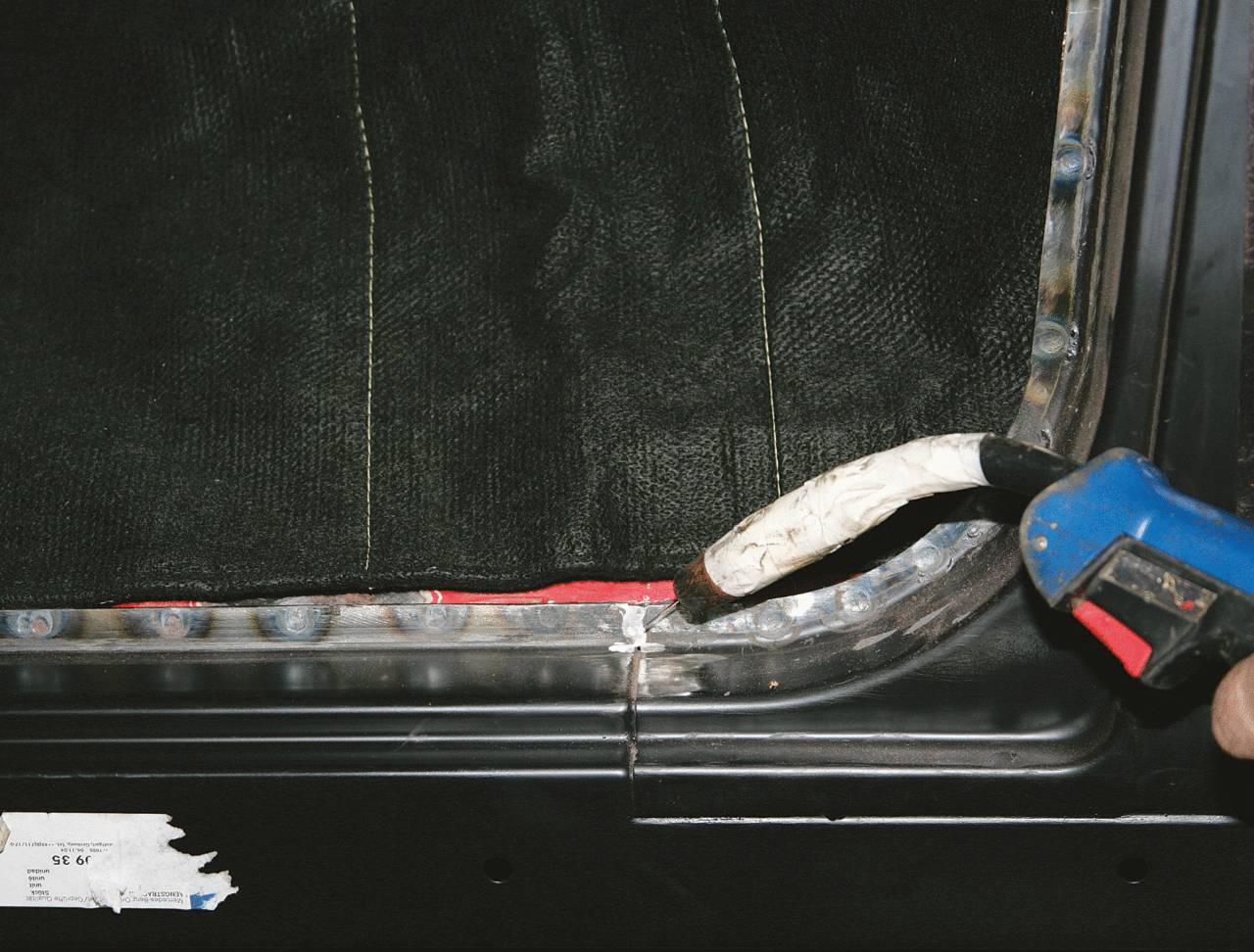 Ein Handgerät wird verwendet, um eine Naht entlang des Randes eines schwarzen Textilmaterials zu versiegeln.