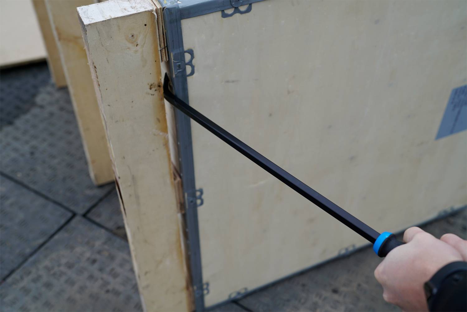Person benutzt einen Brecheisen, um eine Holzkiste zu öffnen.