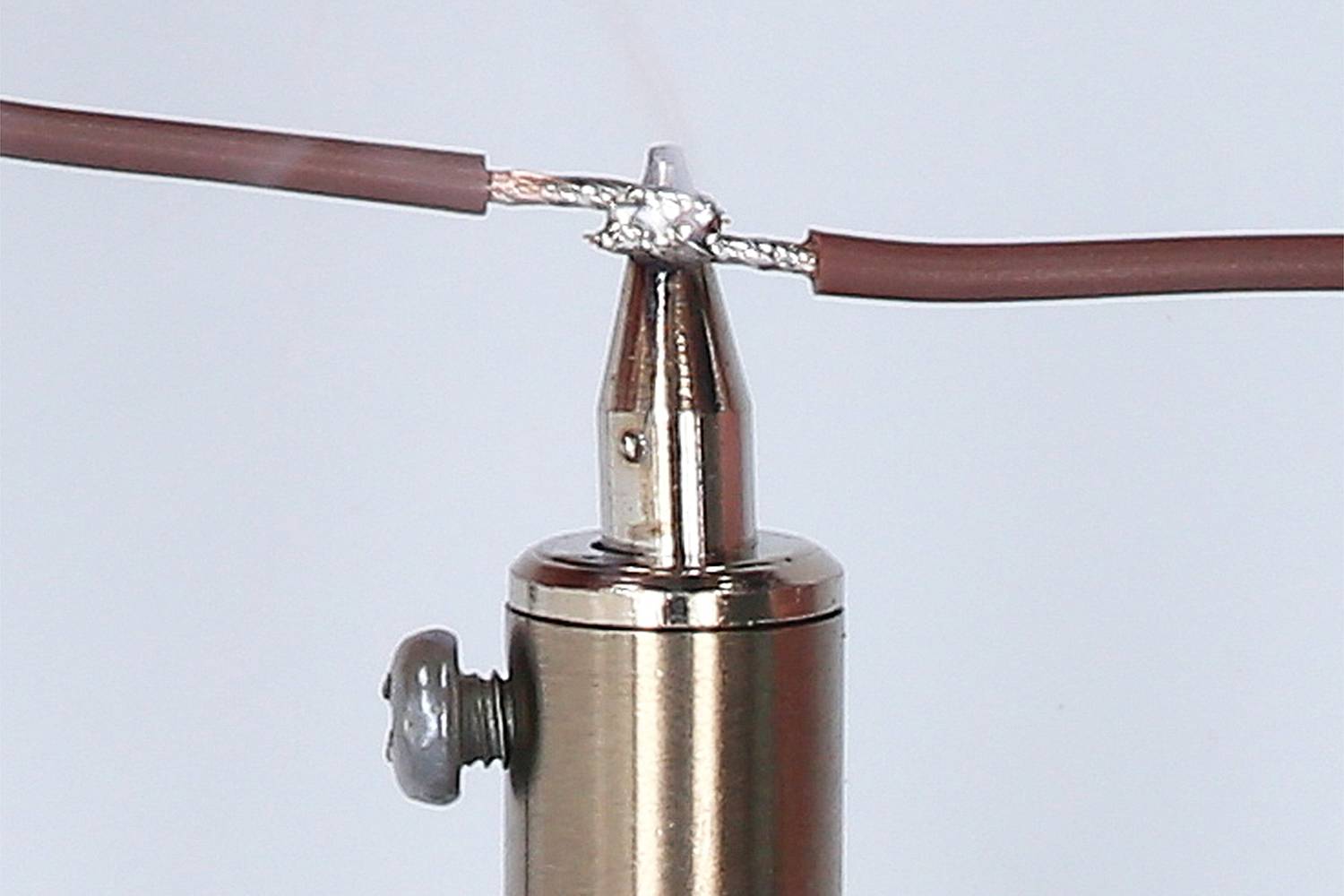 Lötkolben mit Metallspitze verbindet zwei braune Drähte durch Lötmittel.