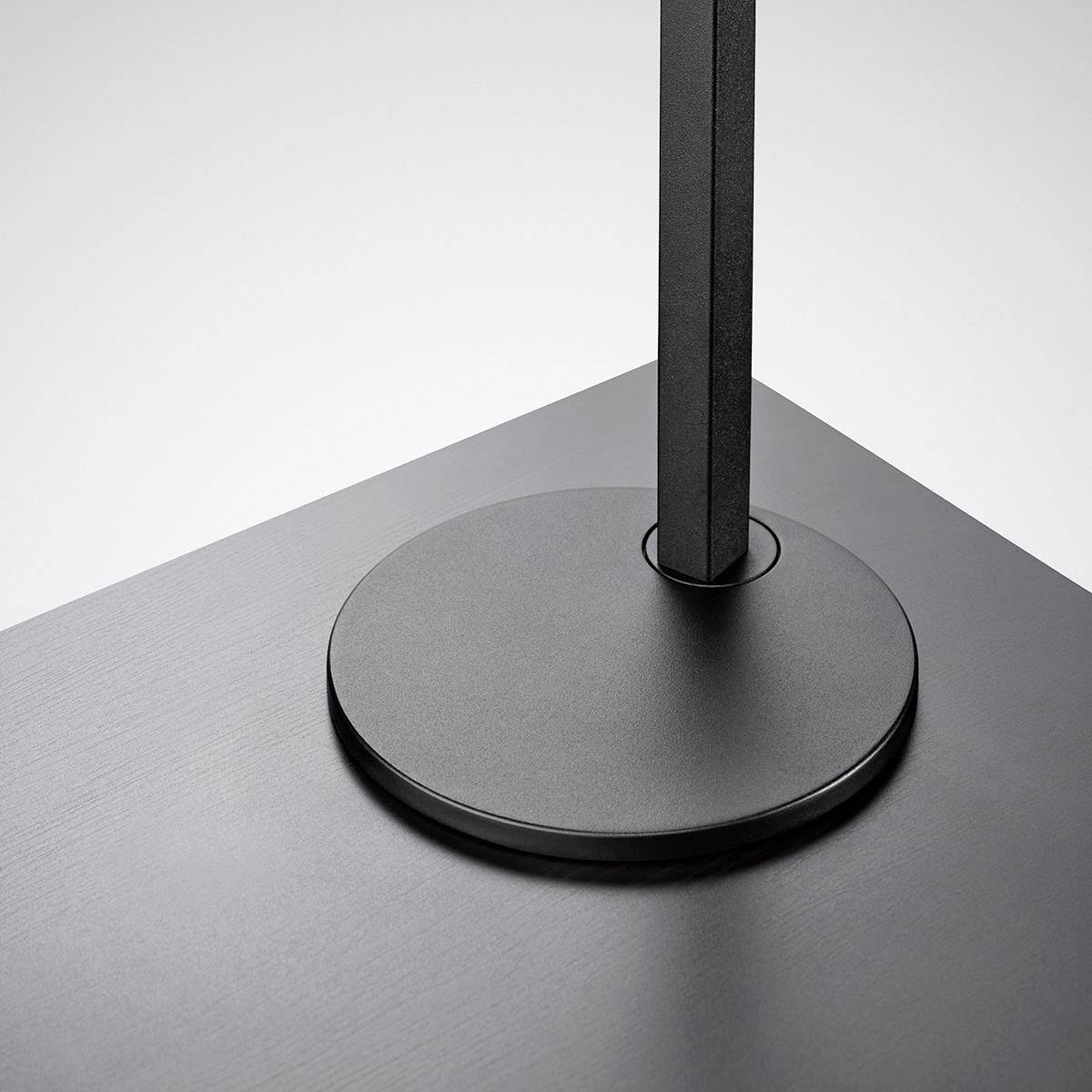 Schwarzer, runder Lampenfuß mit geradem, vertikalem Stand, auf grauem Hintergrund. Minimalistisches Design.