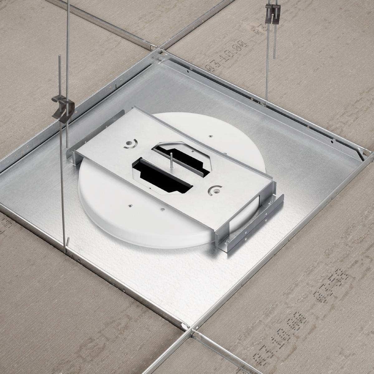 Ein quadratischer Metallrahmen ist in eine abgehängte Decke integriert, mit einem runden, weißen Objekt darin, das für technische Installationen geeignet zu sein scheint.