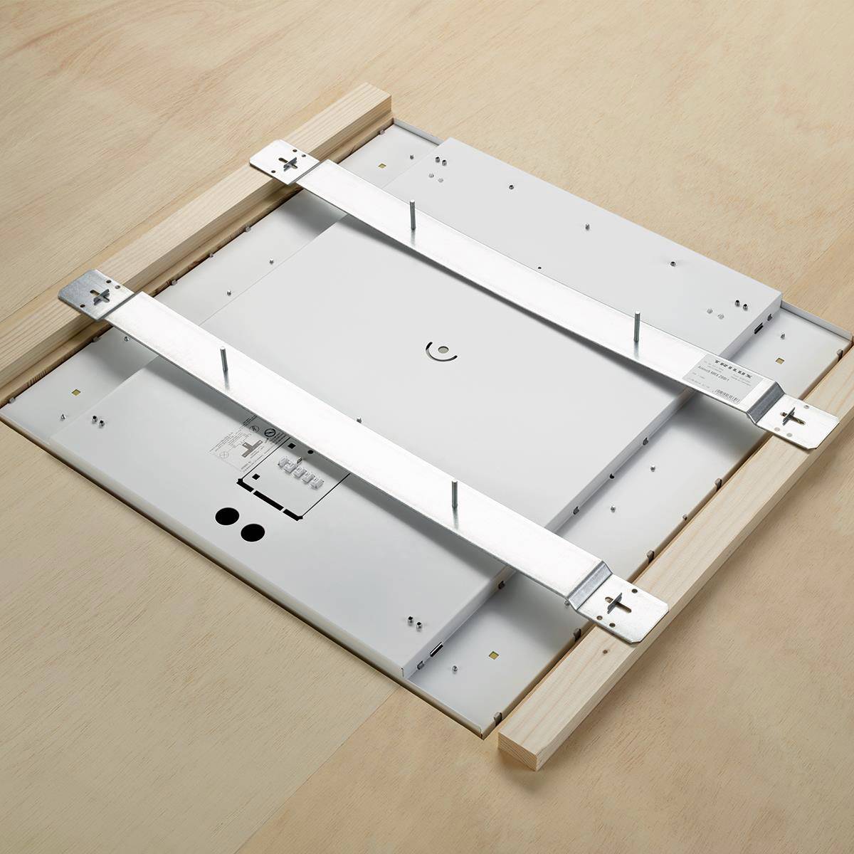 Montagebild einer quadratischen Tischplatte aus hellem Holz mit zwei silbernen Metallquerstreben zur Stabilisierung.