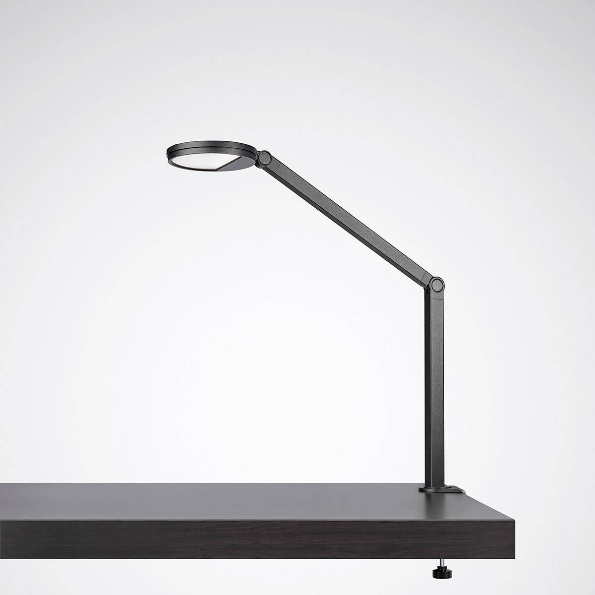 Eine moderne, schwarze Schreibtischlampe mit langem, schwenkbarem Arm steht auf einem schwarzen Tisch. Minimalistisches Design.