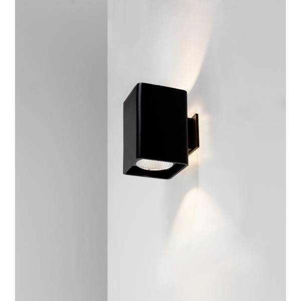 Eine schwarze Wandleuchte, die sowohl nach oben als auch nach unten Licht abstrahlt, montiert an einer weißen Wand.