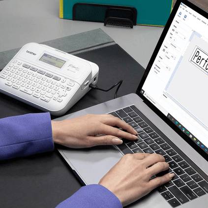 Eine Person tippt auf einem Laptop neben einem Beschriftungsgerät.