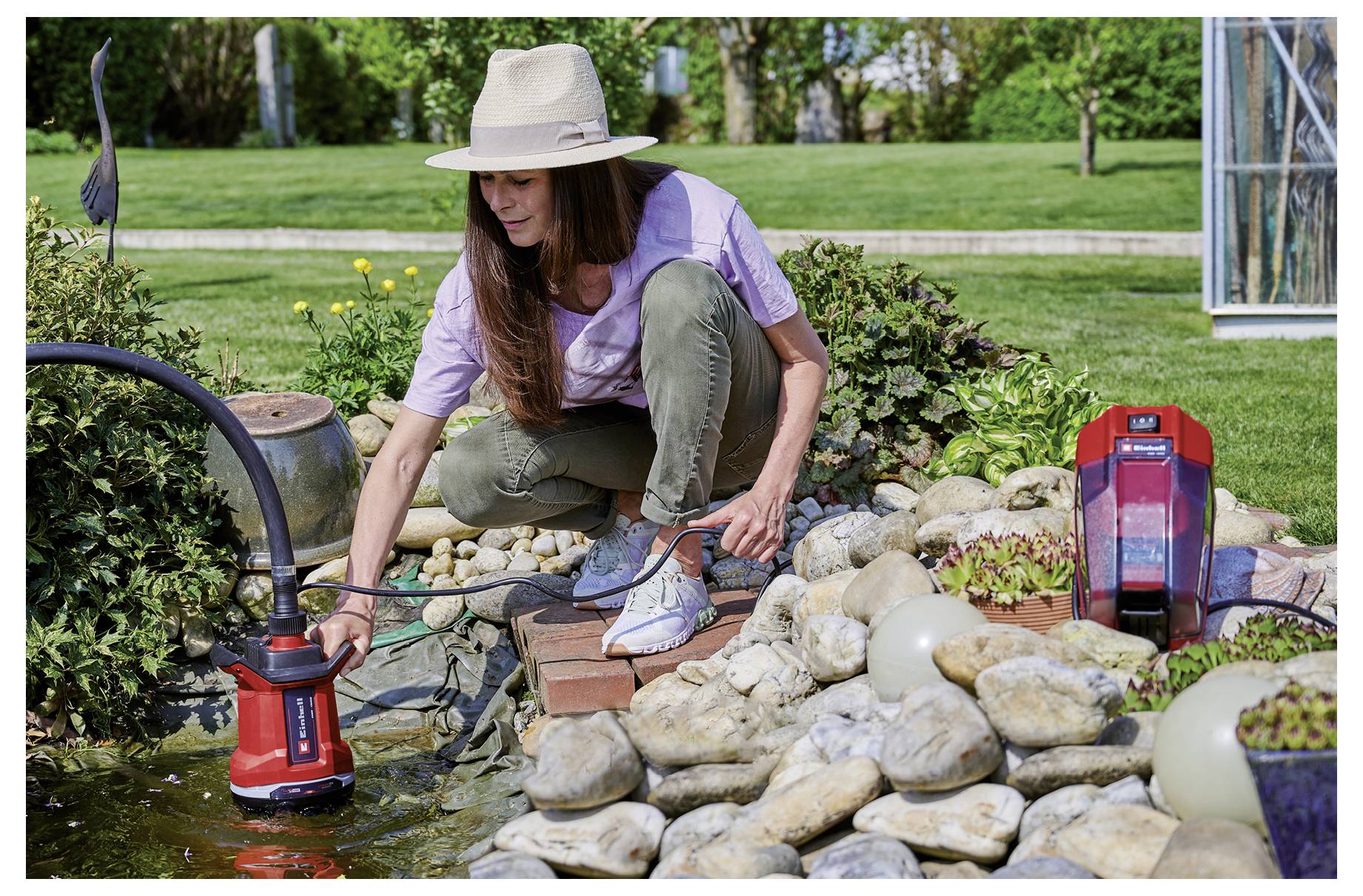 Eine rote Wasserpumpe mit einem Einhell-Logo, schwarzem Griff und Kabel oben, geeignet für den Hausgebrauch.