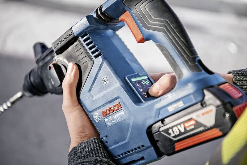 Eine Person hält einen blauen 18V Bosch Professional Akkuschrauber und konzentriert sich auf den Griff und den Bohrer, was einen Einsatz im Bau- oder Heimwerkerbereich andeutet.