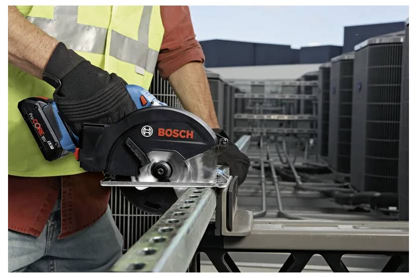 Eine Person, die eine Sicherheitsweste und Handschuhe trägt, verwendet eine tragbare Bosch-Elektrosäge zum Schneiden einer Metallgeländer auf einem Dach in der Nähe von Klimaanlagenanlagen.