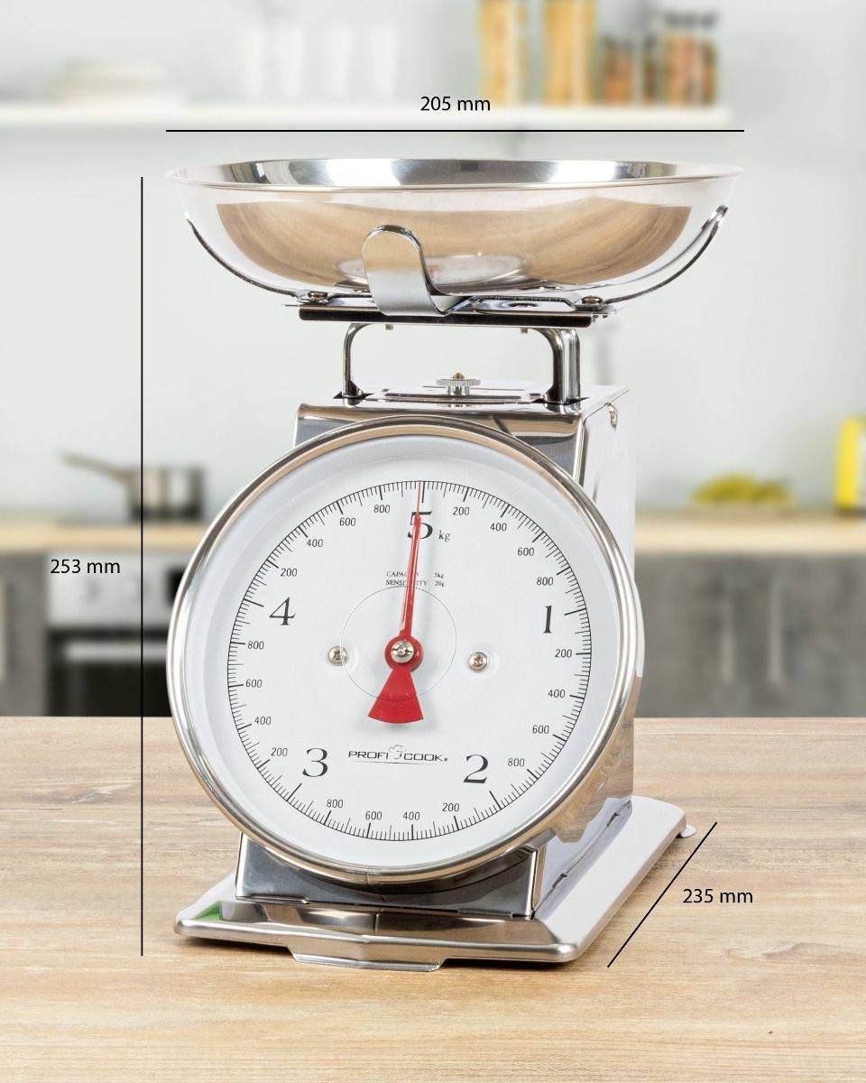 Küchenwaage aus Metall steht auf einem Holztisch, zeigt Maße in Millimetern an: 205 mm Breite, 253 mm Höhe, 235 mm Tiefe.