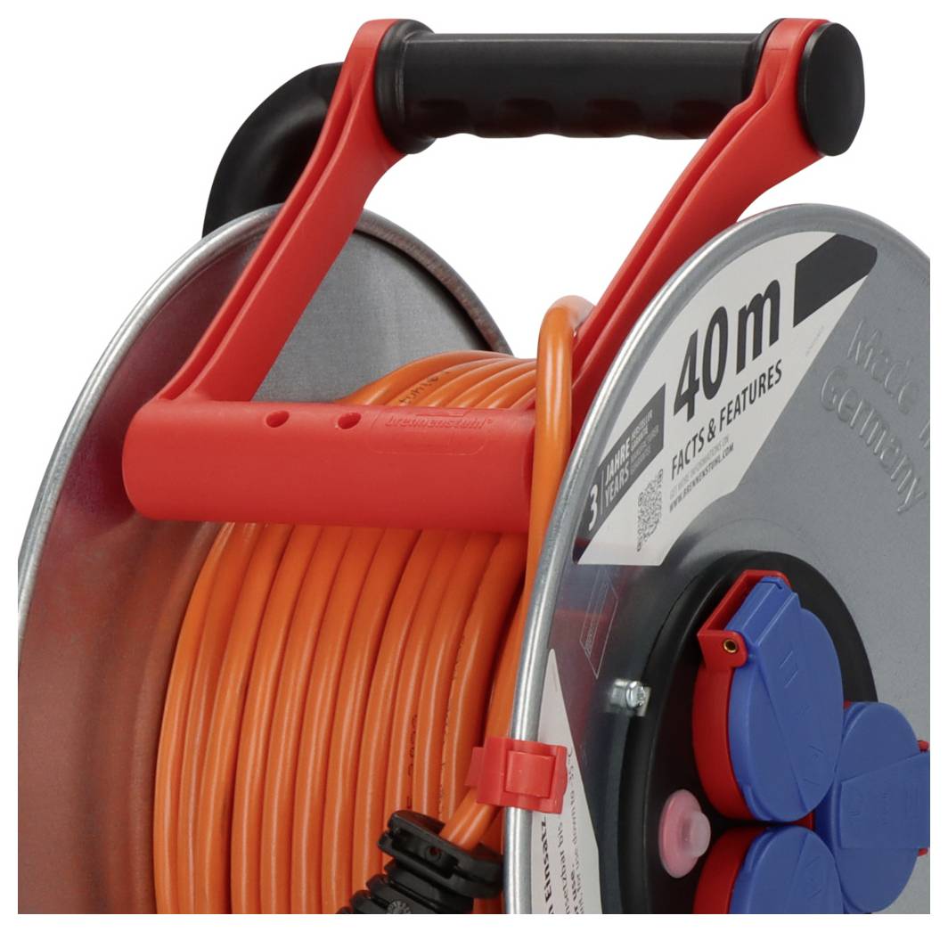 Nahaufnahme einer roten Kabelrolle mit schwarzem Griff, auf der ein aufgewickeltes orangefarbenes Verlängerungskabel und blaue Steckdosen an der Seite angebracht sind.