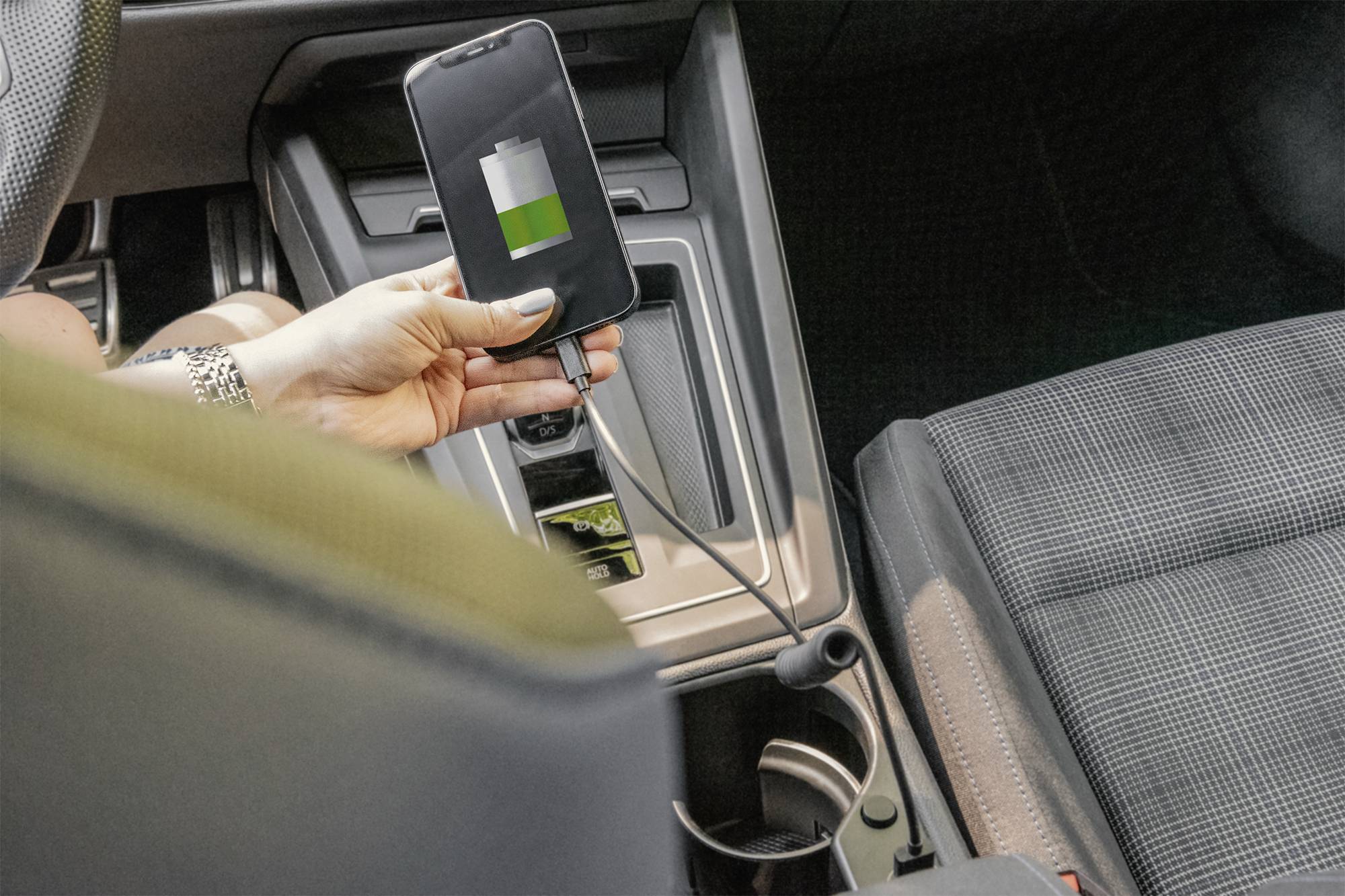 Ein Smartphone wird in einem Auto aufgeladen. Das Display zeigt eine teilweise aufgeladene Batterie an.