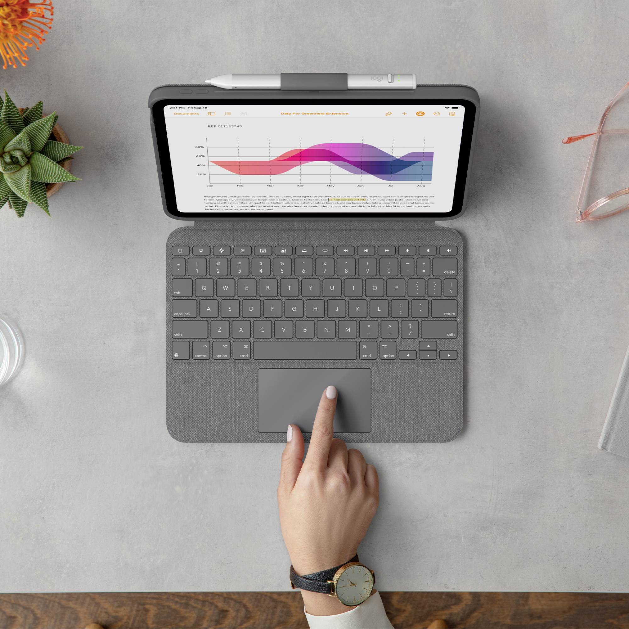 Ein Tablet zeigt ein Diagramm mit steigenden und fallenden Werten. Eine Hand berührt das Trackpad auf einer Tastatur vor dem Tablet.