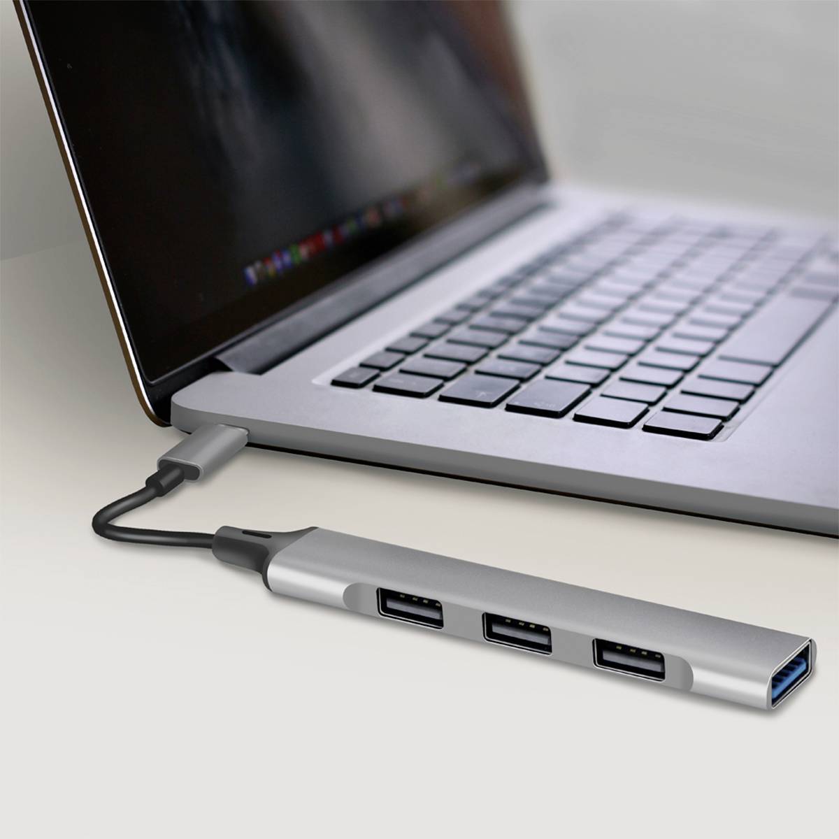Laptop mit USB-C-Dockingstation, verbunden über ein Kabel. Die Dockingstation hat mehrere USB-Ports.