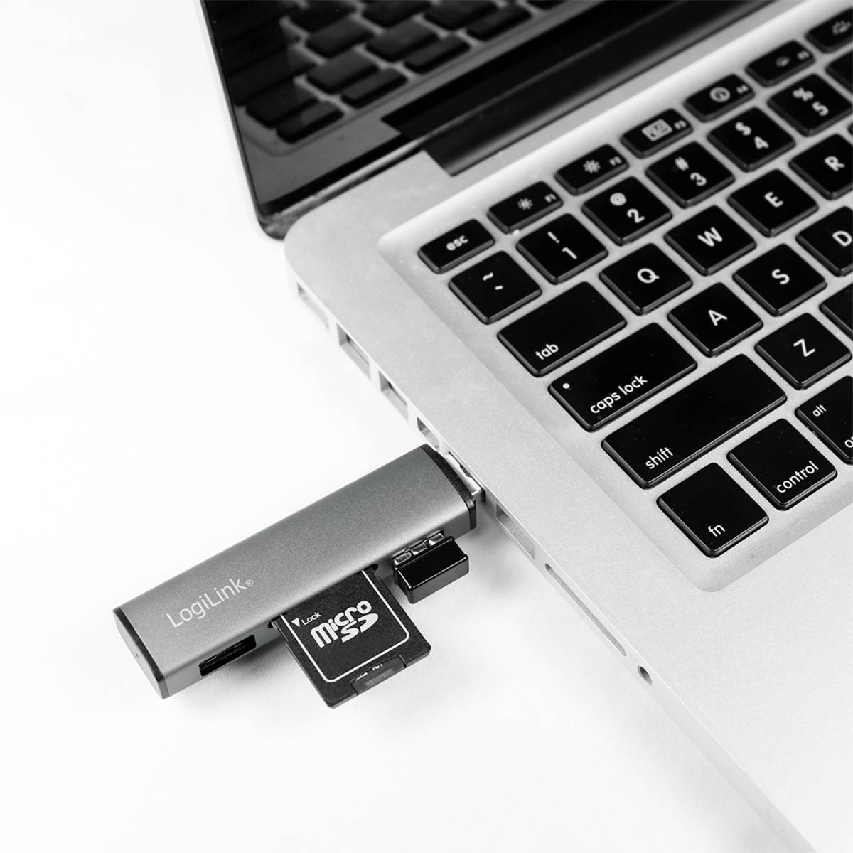 Ein MicroSD-Kartenleser ist an einen Laptop angeschlossen. Der Adapter hat einen 'LogiLink'-Schriftzug und eine eingesteckte MicroSD-Karte.