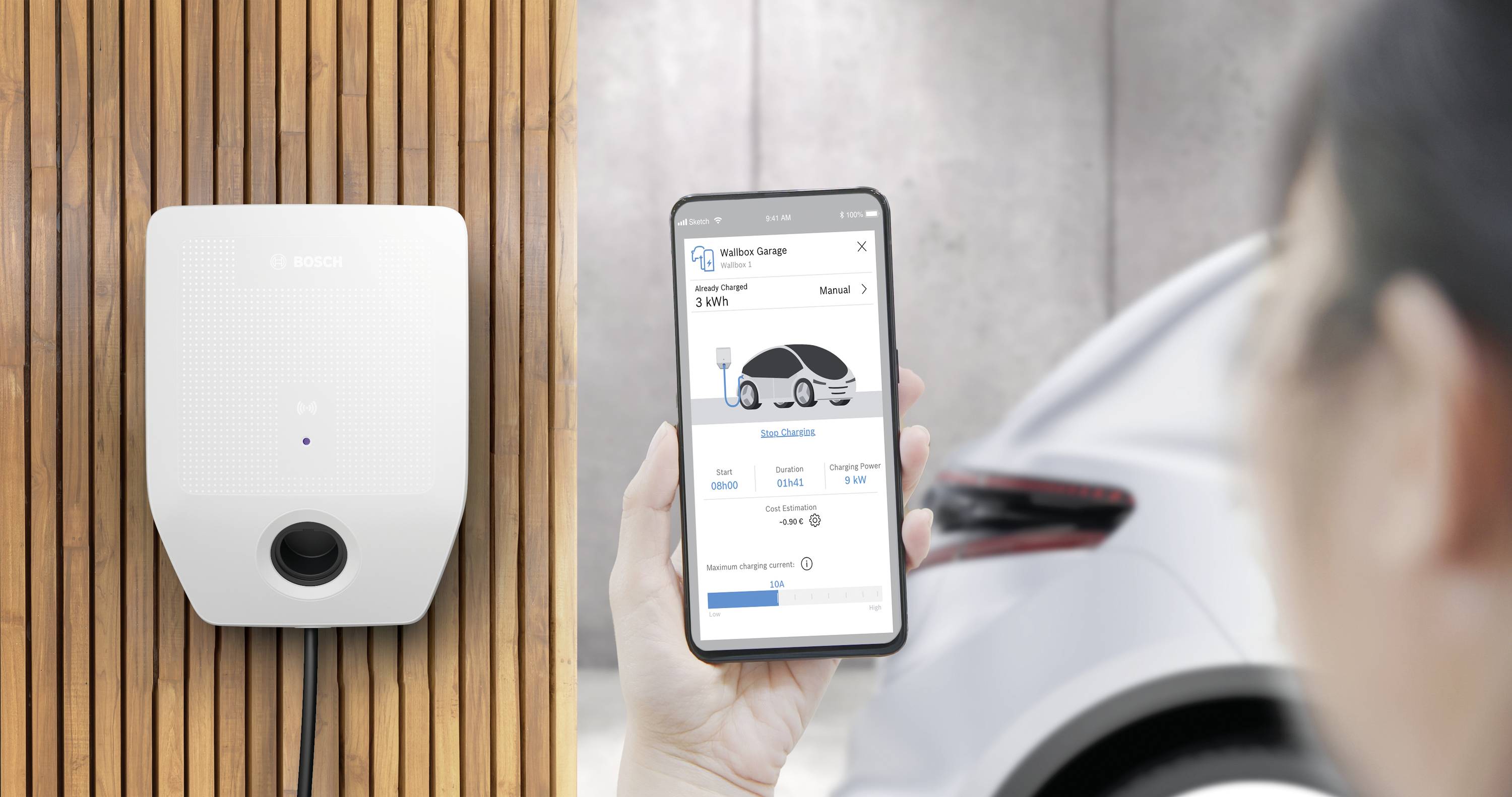 Eine Person verwendet eine Smartphone-App, um einen Ladevorgang für ein Elektrofahrzeug an einer Wandladestation zu überwachen.