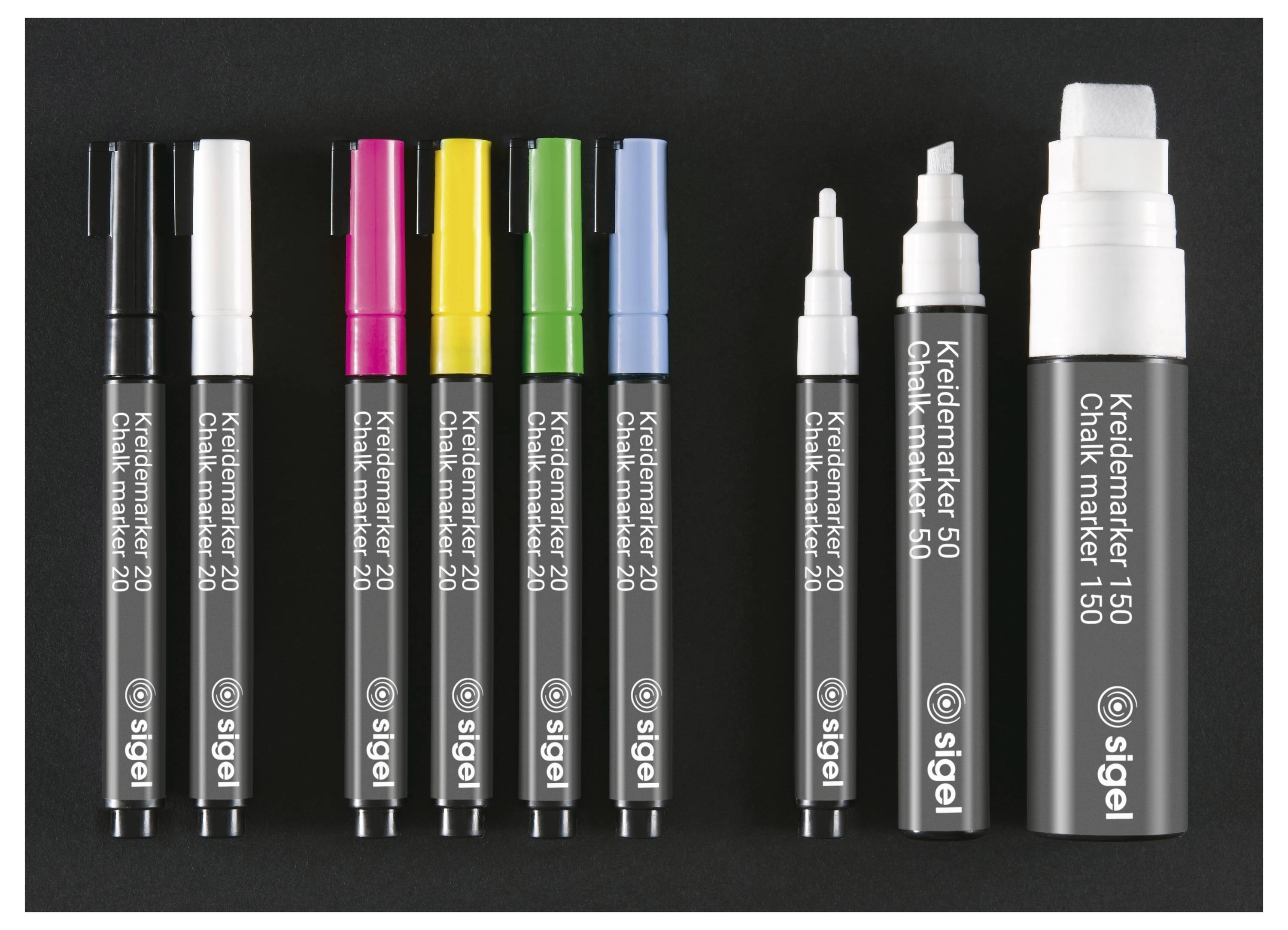 Sortierte Kiedlmarker 20 und 150 Marker in Schwarz, Weiß, Rosa, Gelb, Grün und Blau, plus zwei Markerstifte mit weißer Spitze, aufrecht auf dunklem Hintergrund angeordnet.