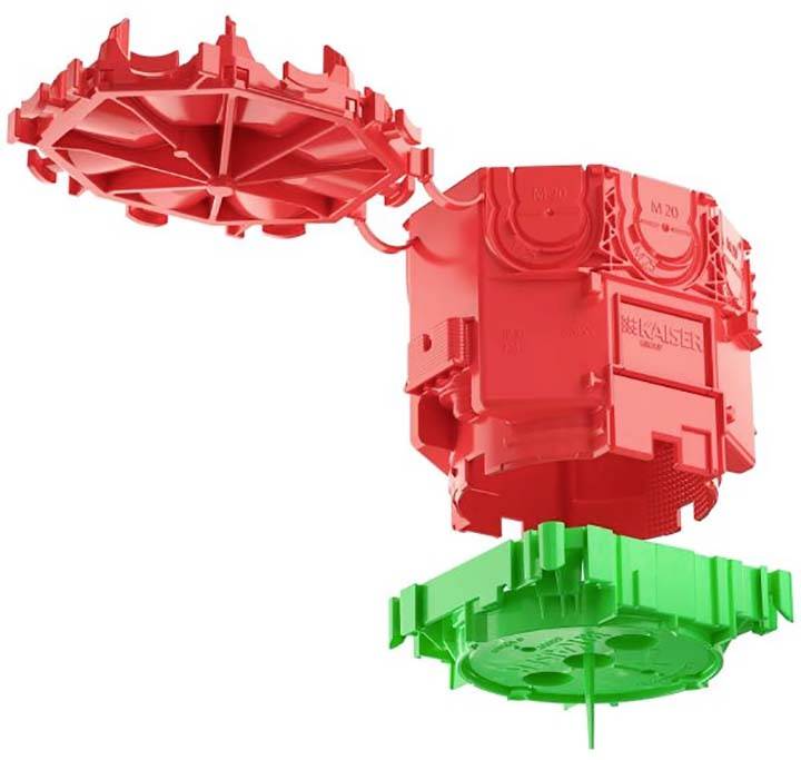 Zwei Kunststoffteile, rot und grün, die aneinander passen. Ein Bauteil mit quadratischer Form und ein rundes, scheibenförmiges Teil.