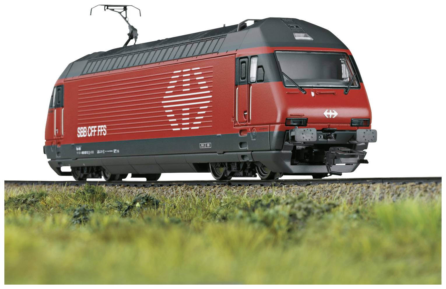 Roter Zug der SBB mit Stromabnehmer auf Gleis, seitlich fotografiert. Vordergrund aus Gras, blauer Himmel im Hintergrund.