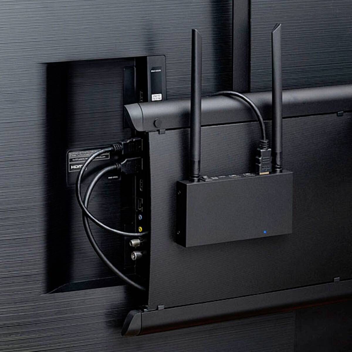 Ein drahtloser Router ist an der Rückseite eines Fernsehers montiert. Verschiedene Kabel sind an den Router und den Fernseher angeschlossen.