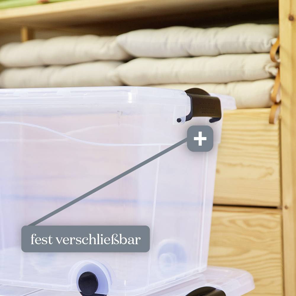 Eine durchsichtige, fest verschließbare Aufbewahrungsbox mit Rollen, steht vor einem Regal voller gefalteter Decken.