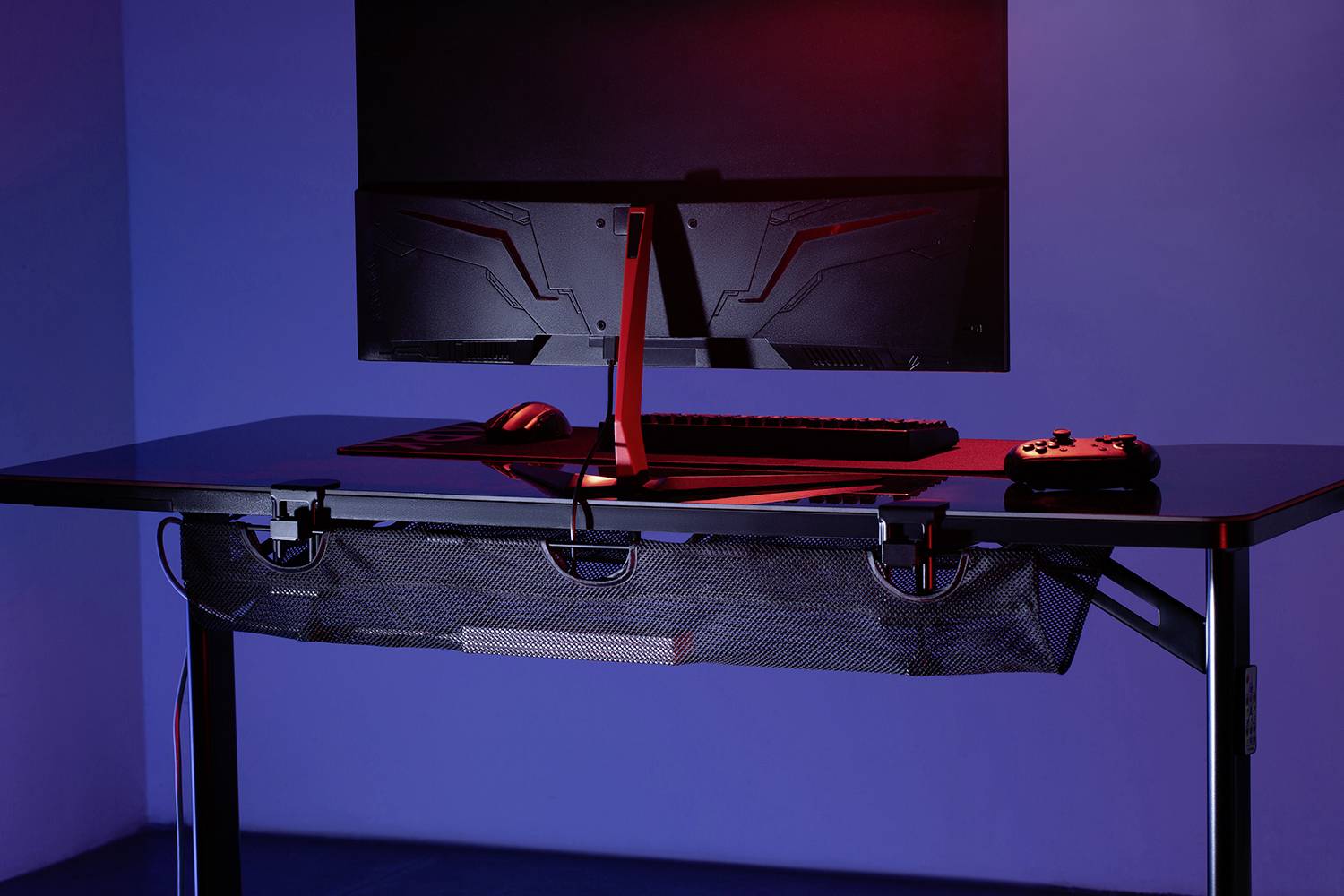 Ein moderner Schreibtisch mit Computerbildschirm, Tastatur und Gamecontroller. Rote Beleuchtung verleiht dem Raum eine futuristische Atmosphäre.