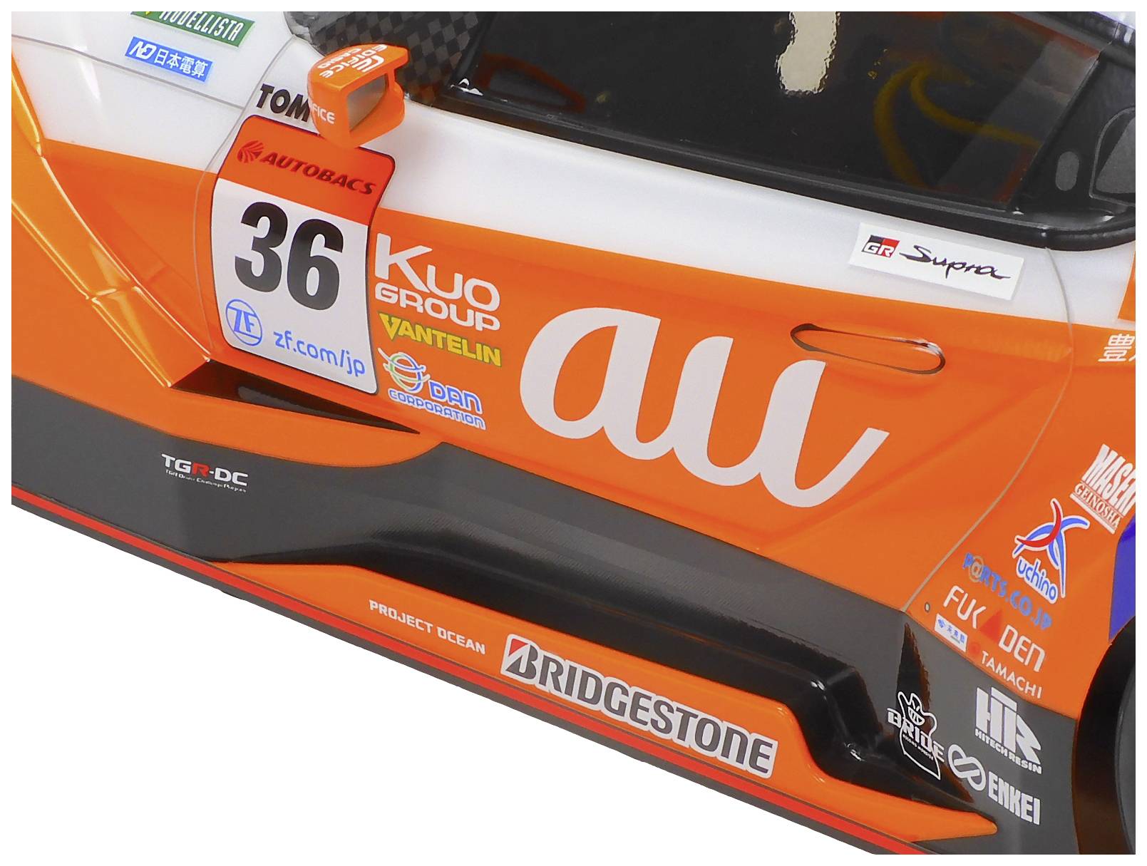 Rennwagen mit orange-weißer Lackierung und der Startnummer '36'. Sichtbare Sponsorenlogos und technische Details an der Seite.