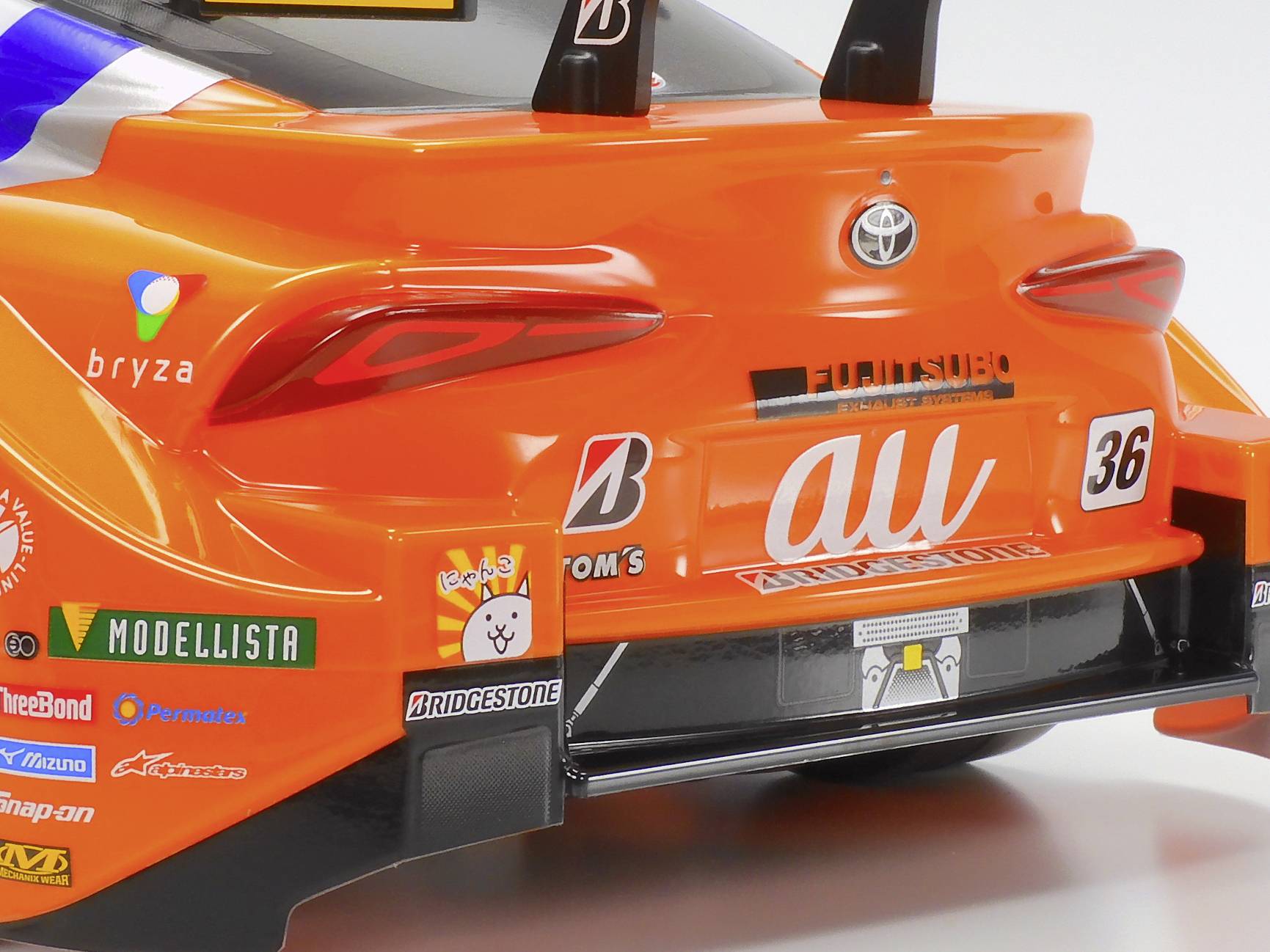 Spielzeugauto in Orange, Nachbildung eines Rennwagens. Die Rückseite zeigt Markenlogos und Startnummer 36.