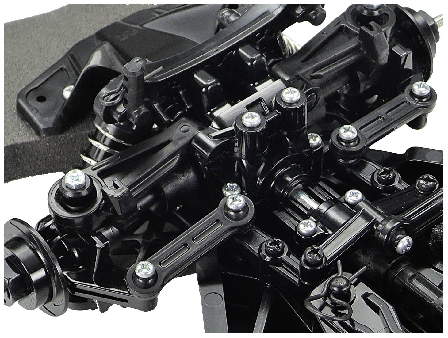 Nahaufnahme eines komplexen, schwarzen mechanischen Bauteils mit mehreren Schrauben und Gelenken, wahrscheinlich Teil eines Fahrzeugs.