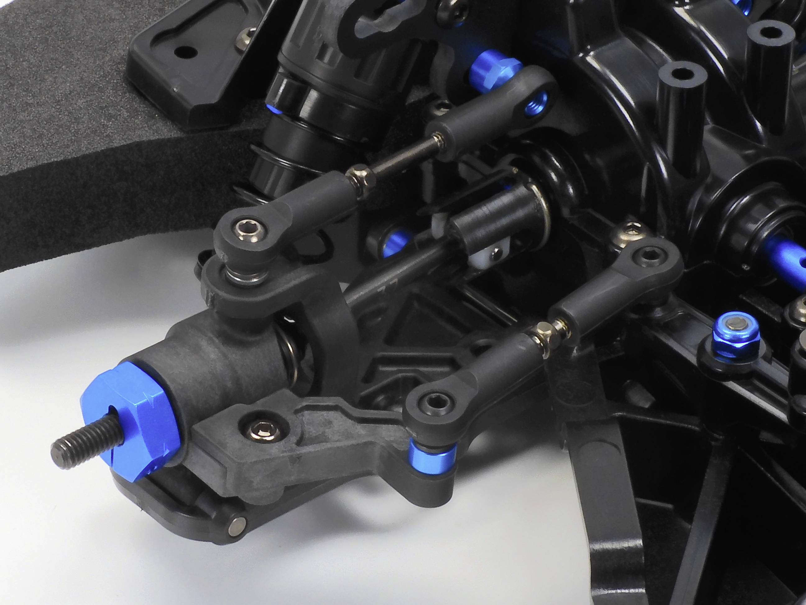 Nahaufnahme eines technischen RC-Auto-Bauteils mit Gelenkverbindungen und Schrauben, zeigt Details der Aufhängung und Mechanik.